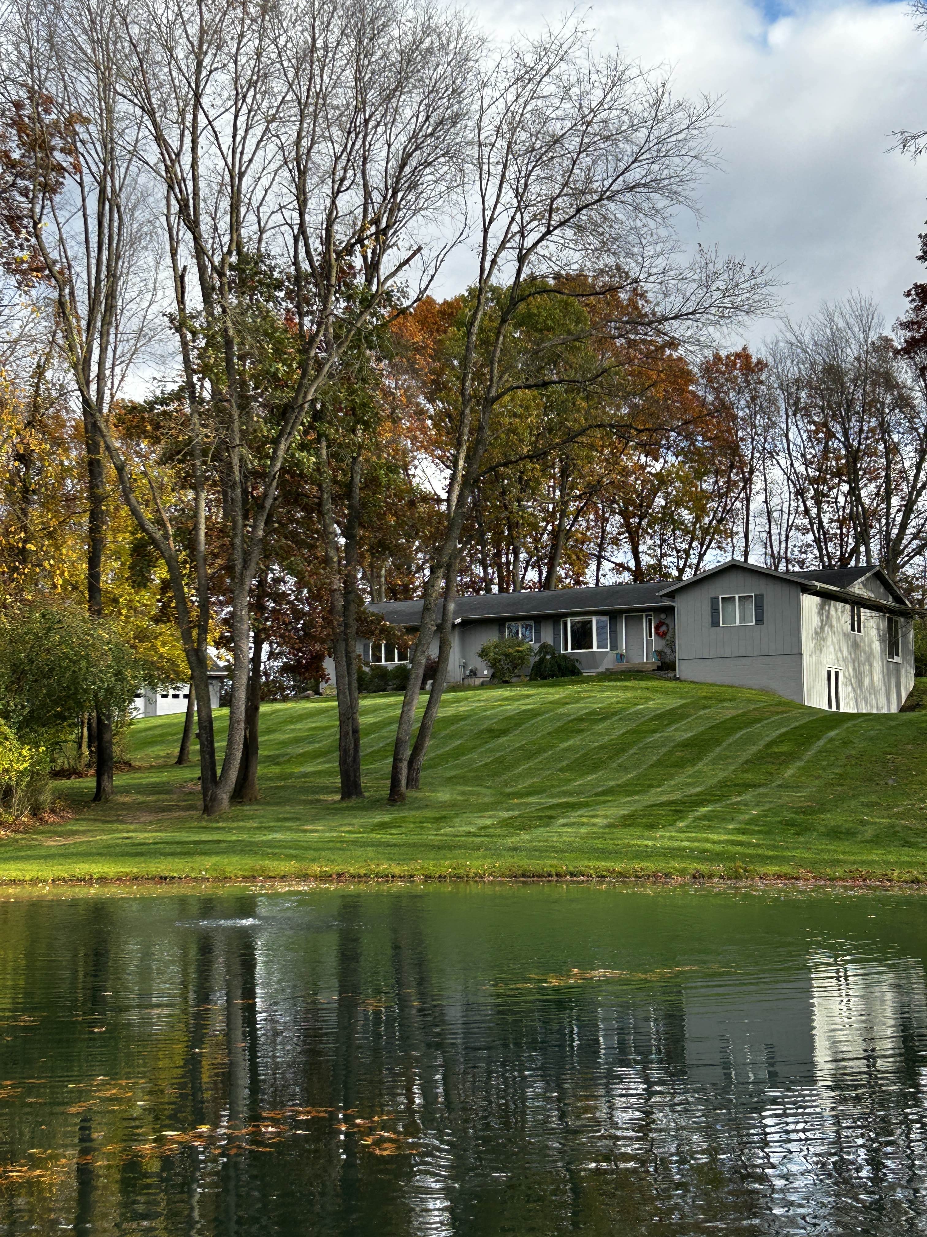 Lakefront property with striped lawn and fall foliage